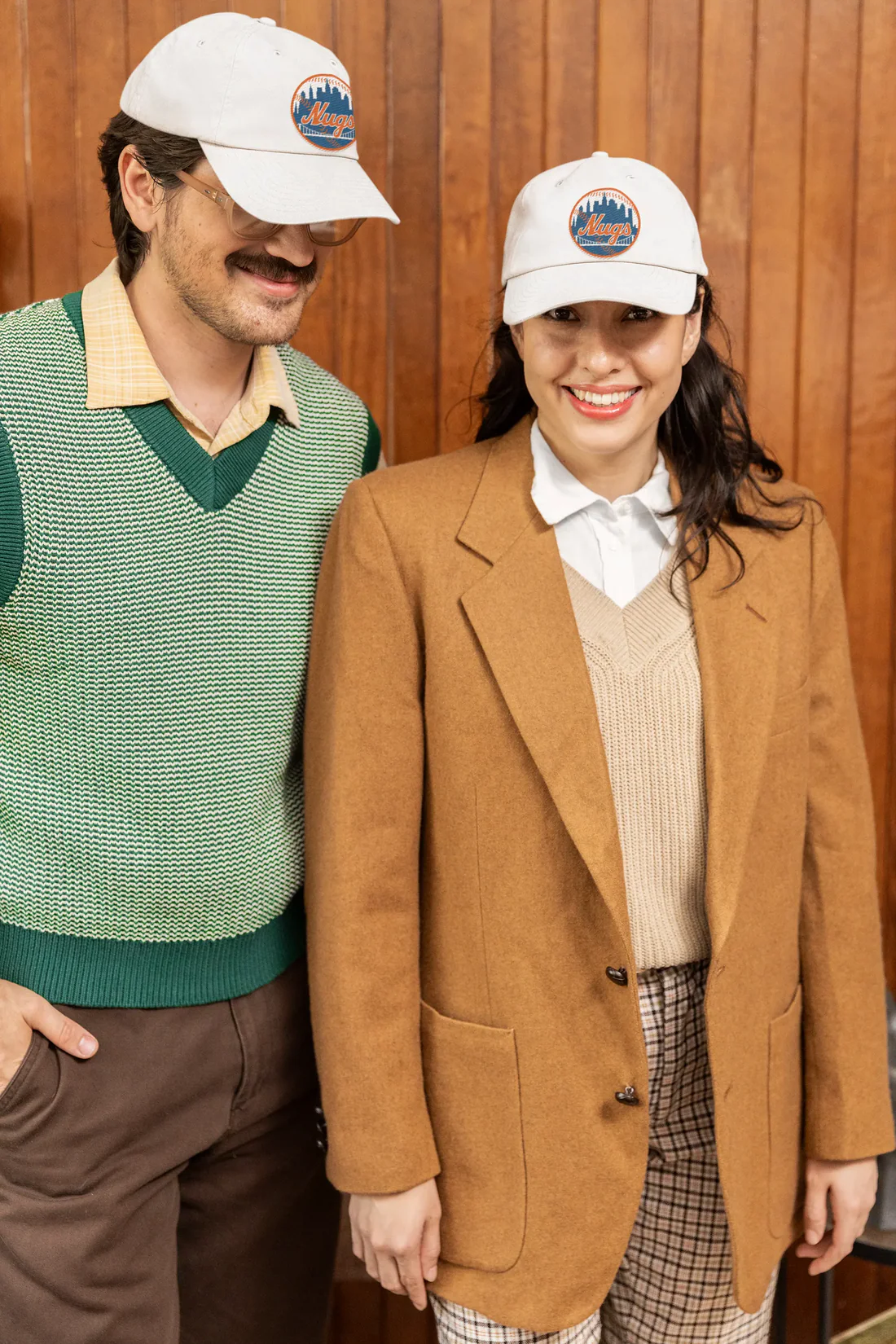 Two people wearing New York Nugs Dad Hats with retro-style outfits indoors

