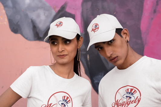 Two models wearing matching white New York Nuggets dad hat and logo t-shirts against a colorful mural