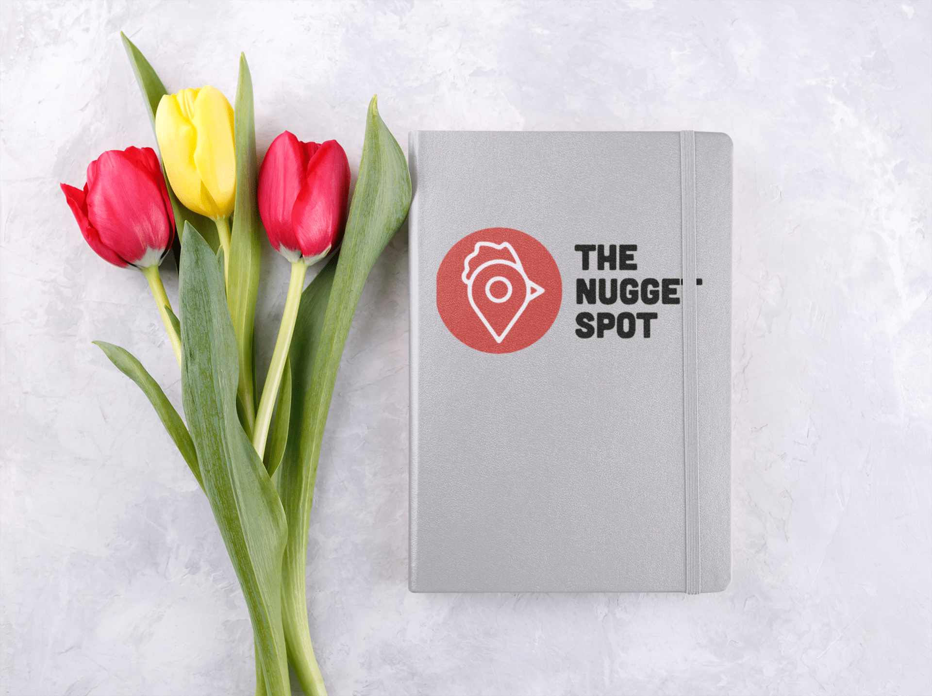 Gray hardcover notebook with The Nugget Spot logo beside red and yellow tulips.