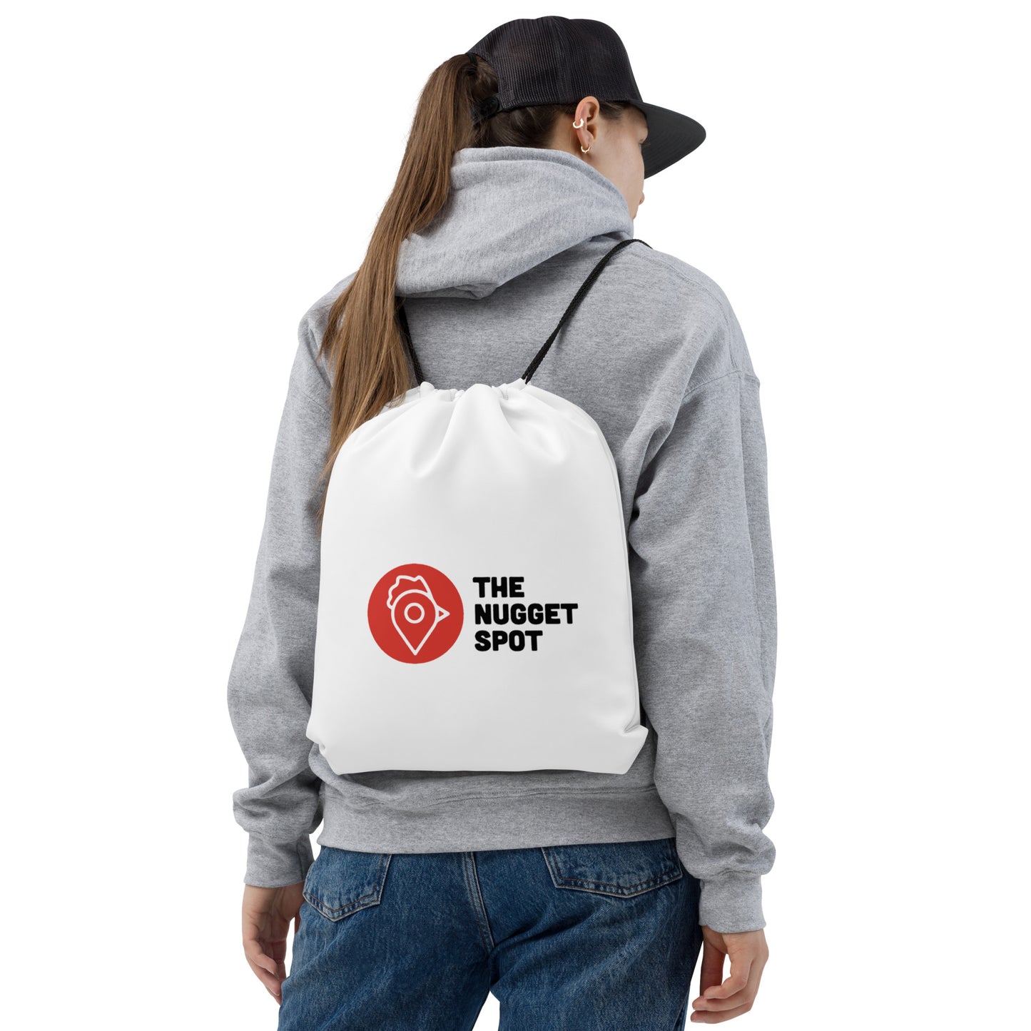 Woman wearing hoodie and cap with The Nugget Spot Drawstring Bag on her back
