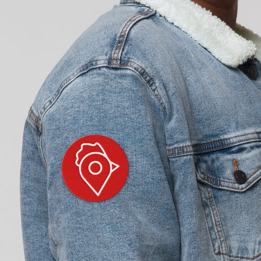 Close-up of The Nugget Spot red embroidered patch on denim jacket sleeve.