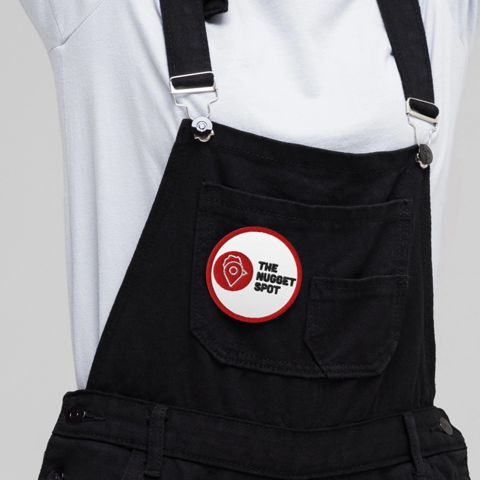 Close-up of The Nugget Spot 3-inch iron or sew-on embroidered patch – detailed red and black logo on white twill backing.