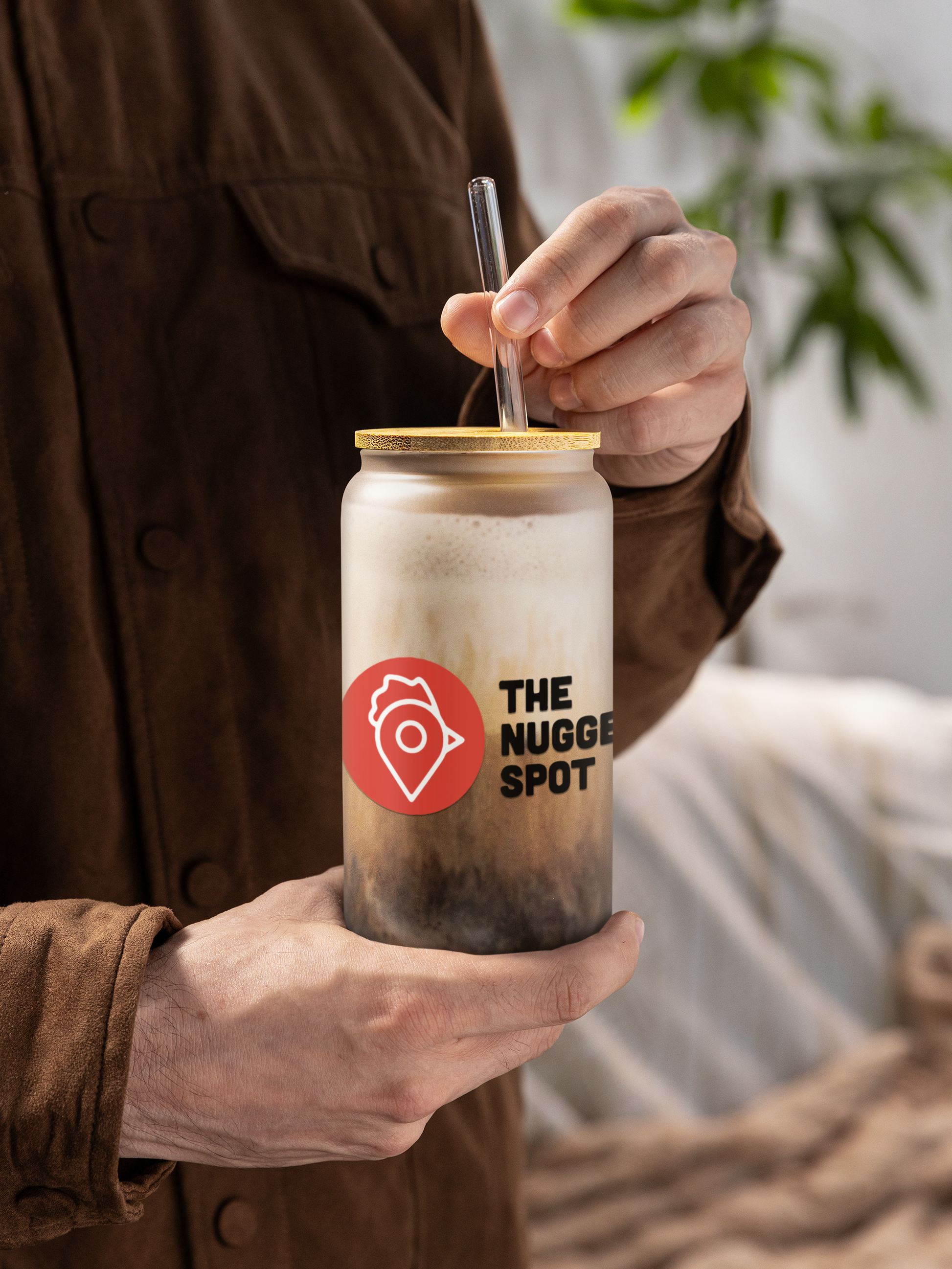 Close-up of The Nugget Spot 16oz can-shaped glass with frothy iced latte and straw
