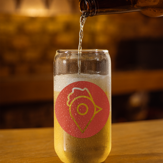 A clear glass with The Nugget Spot red logo being filled with a cold beverage at a bar counter.