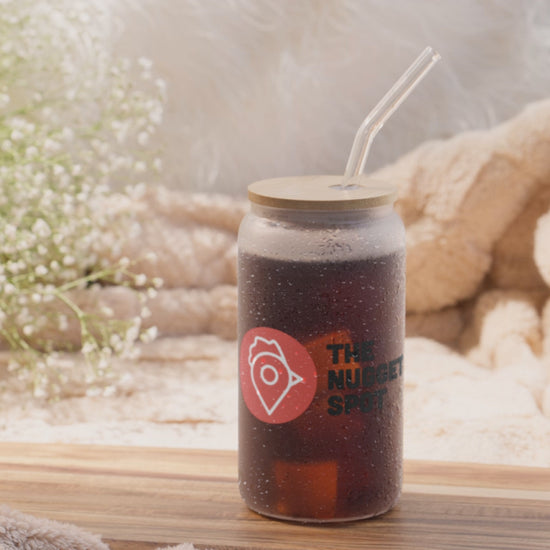 View of The Nugget Spot 16oz can-shaped glass with optional bamboo lid and straw, highlighting UV-printed logo and glass details