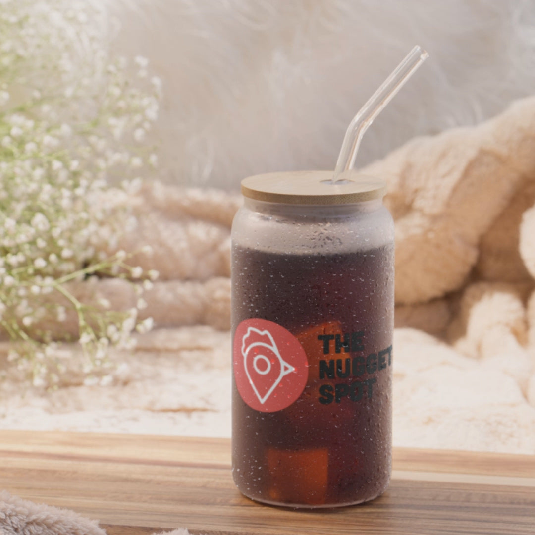 View of The Nugget Spot 16oz can-shaped glass with optional bamboo lid and straw, highlighting UV-printed logo and glass details