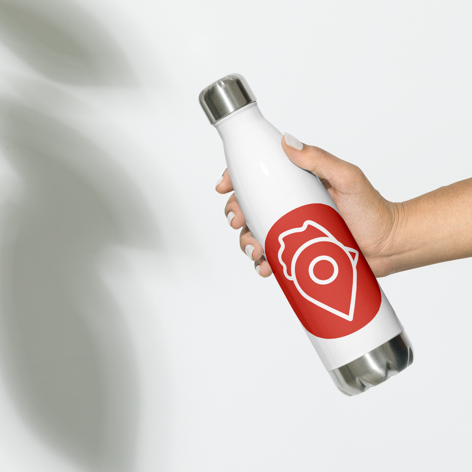 Hand holding white version of The Nugget Spot Signature stainless steel water bottle with red logo.